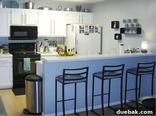After kitchen makeover with glossy white cabinets, cool gray walls, and modern bar stools