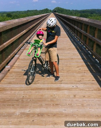Bridge Views and Verdant Vistas 7 Parent riding a bicycle with a child in a front-mounted bike seat