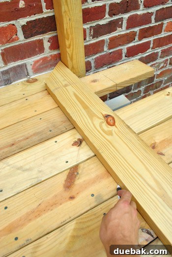 Crafting Your Perfect Outdoor Deck 6 Marking the cut line with a pen using a guide piece.