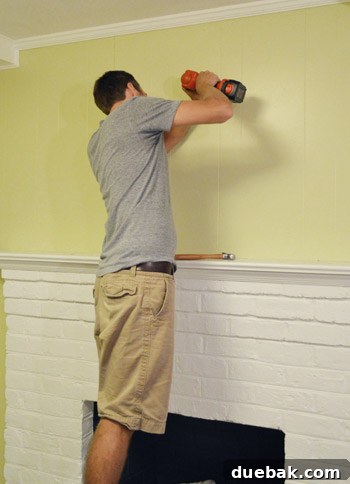 Mirroring Elegance Above the Mantel 8 John driving screws into the wall for the mirror installation.