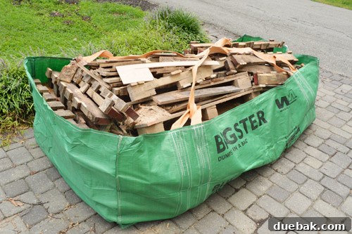 Full Bagster on the driveway, packed with wood