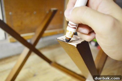 Sanding and touching up the edges of the table legs with a marker