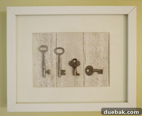 Close-up of framed antique keys arranged in a family representation, with one tall, one medium, and two small keys on a wood-grain background.