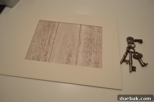 Wood-grain paper taped behind a white mat inside a picture frame.