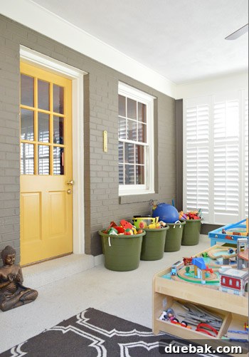 Sunroom converted into a vibrant playroom with colorful walls, toy baskets, train table, and custom window shutters