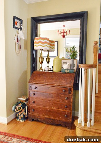 Entryway featuring a mirror reflecting a red chandelier, a cherished wedding decor item repurposed for the home