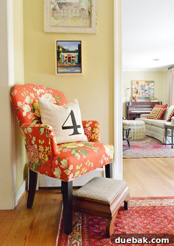 Entryway vignette with a decorative pillow featuring a meaningful number and an antique chair with new upholstery