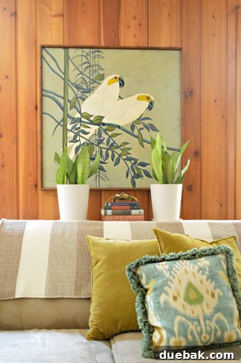 Framed secondhand art above a sofa with a throw blanket from an Etsy shop, adding to the family room's eclectic decor
