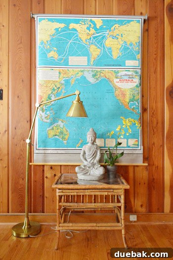 Bright teal map on a wood-paneled wall with a chic gold lamp, an eBay find that adds color and sophistication