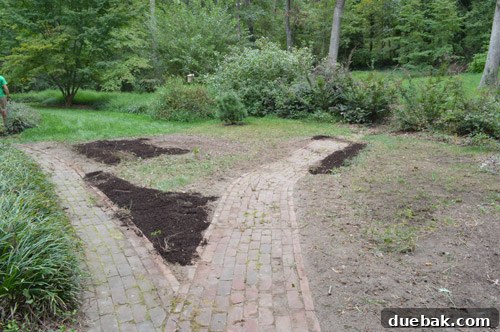 Adding topsoil to fill uneven spots in the backyard before seeding, ensuring a level surface