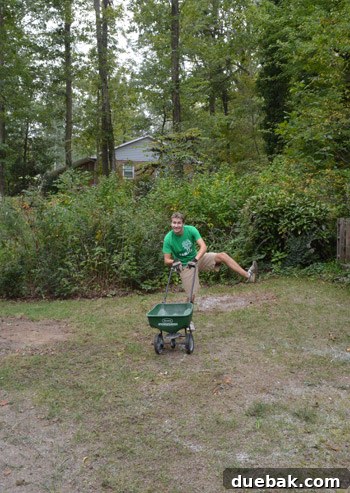 John spreading grass seed with a broadcast spreader in the backyard, demonstrating his seeding technique