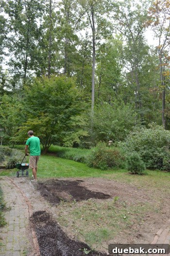 Close-up of John spreading Scott's Tall Fescue Mix seed in the backyard, showing the broadcast spreader