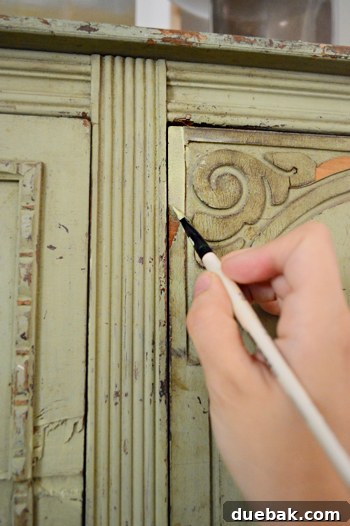 Perfectly Blending New and Existing Paint 5 Hand applying paint to a damaged area of the buffet with a small brush