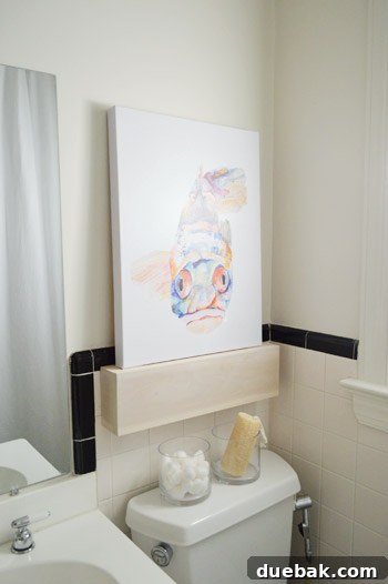 Shelf Your Tile Troubles: A DIY Cover-Up 11 Whitewashed floating shelf above the toilet, with the fish painting.