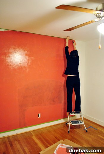A vibrant wall painted 'Moroccan Spice' in a playroom, with an 'N' initial on a shelf.