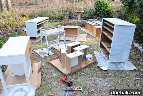 Furniture pieces undergoing priming in a backyard, humorously called a 'furniture graveyard'.