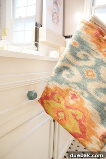 Elevate Your Windows with Frosting 12 Fabric swatch, new green-jade-like knob, and a fish canvas art piece in a bathroom setting