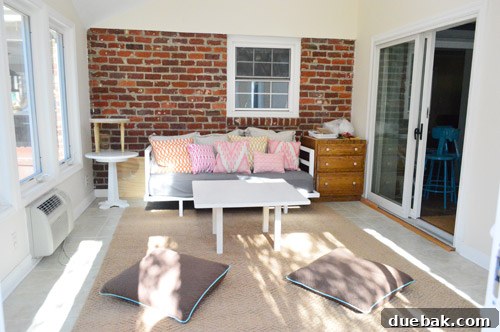 The sunroom with the jute rug, daybed, and various pillows, showing an initial attempt at styling and defining the space's comfort zones.