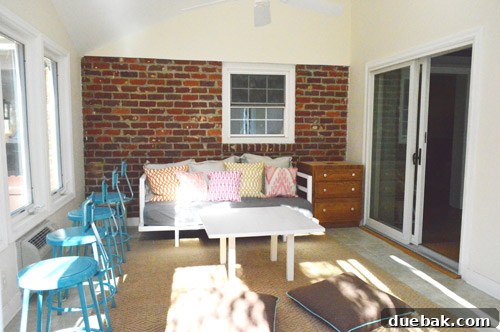 The bright blue stools placed near the daybed and windows in the sunroom, illustrating how the initial bar concept felt cramped and dysfunctional.