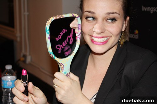 Sherry Petersik signing a mirror with hot pink lipstick for a fan.