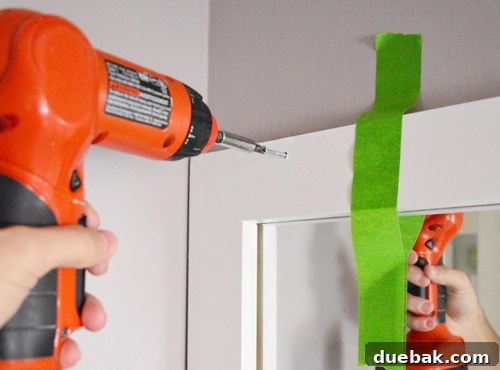 Securing the mirror frame to the wall with screws