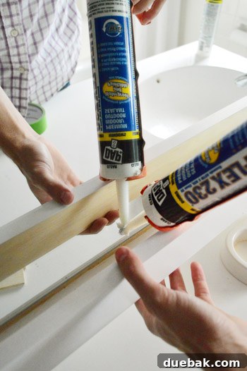 Applying silicone caulk to the bottom of the mirror frame for added stability