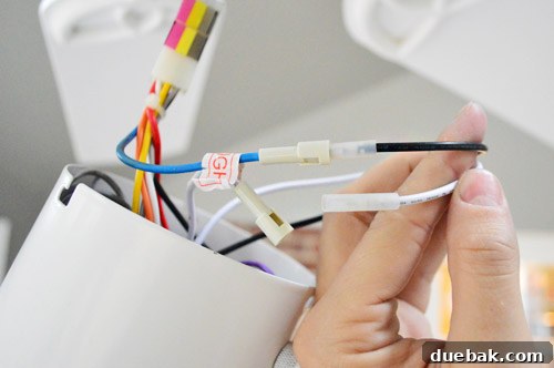 Electrical wires from the light kit being connected to the ceiling fan's pre-wired connections