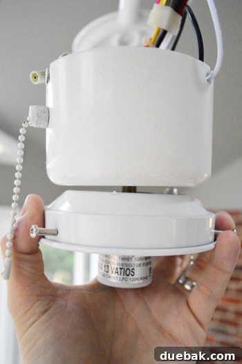 Light fixture's threaded rod (nipple) being carefully screwed into the ceiling fan cover