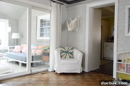 View from the living room into the sunroom after painting the brick gray, demonstrating the improved aesthetic.