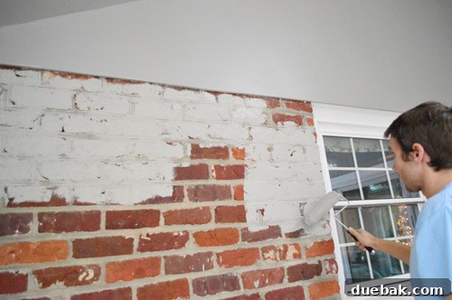 Roller application of gray paint on the textured brick surface, part of the efficient painting process.