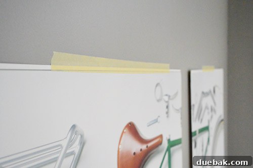 Close-up of the bicycle prints held by masking tape, showing the temporary nature of their display.