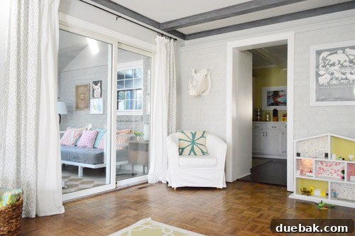 Panoramic view of the sunroom from the living room, showcasing the newly decorated space with art on the walls.