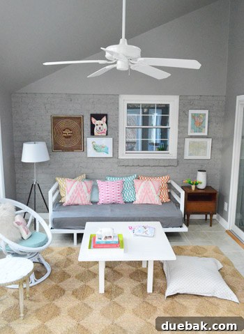 A curated collection of eclectic art frames and objects displayed on a brick sunroom wall.