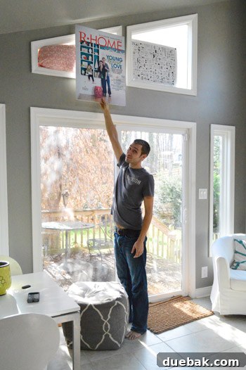 A person holding a large poster, seemingly to diffuse light for photography, illustrating a DIY lighting solution.