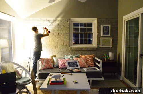 A dark, blurry photo showing an art piece being hung on a brick wall at night, illustrating the challenging lighting conditions.