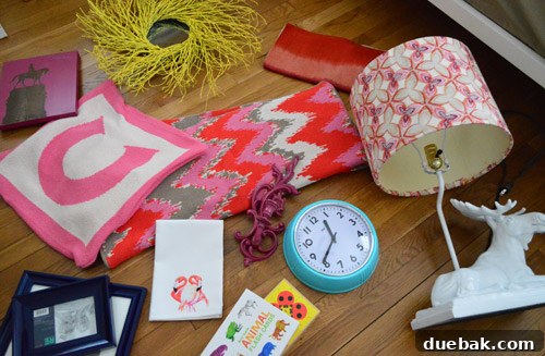 A collection of fabric swatches, decor items, and accessories in pink, red, white, and navy for Clara's room