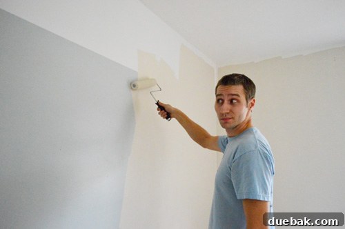 John rolling paint onto the walls, covering previous random colors and stencils