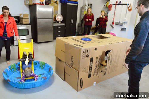 A makeshift indoor playground in a garage, featuring a slide and baby pool, entertaining kids during Christmas