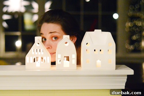 A set of white porcelain cottage lanterns displayed on a mantelpiece