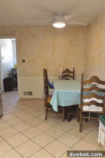 Dated kitchen breakfast nook before renovation, showing old wallpaper and chair rail