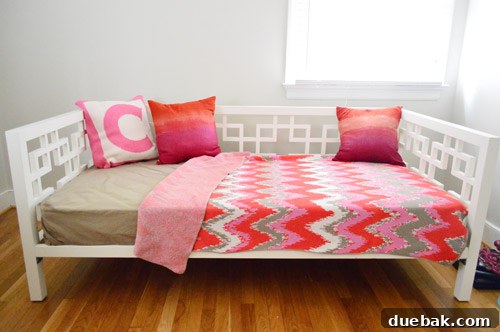 A cozy daybed adorned with decorative pillows and a blanket, showcasing how the upholstered lampshade's colors complement the room's textiles.