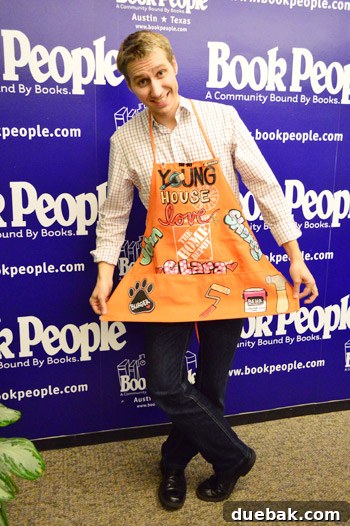 Man doing a 'murtsy' while holding a custom Home Depot apron