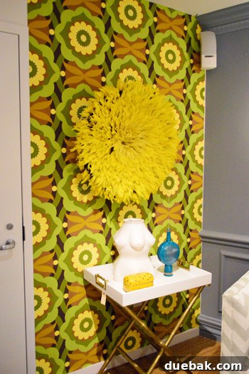 Retro-inspired wall decor featuring vintage wallpaper and a large feathered wall hanging, showcasing eclectic design.