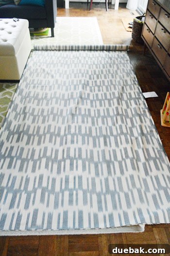 DIY No Sew Ikat Curtains for Playful Kids Spaces 6 Fabric being unrolled on the floor for measurement and cutting