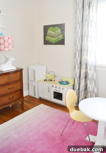 Framed poncho hanging above a play kitchen in a child's room