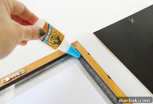 Super glue bottle next to a framed glass, illustrating the gluing process