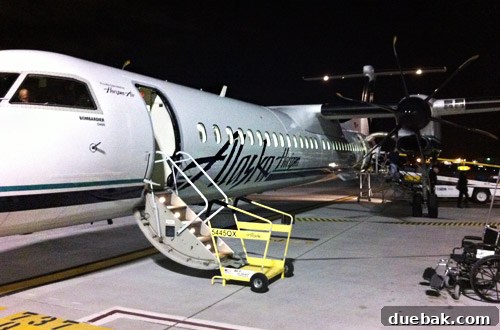 A night shot of the airplane wing over a city, representing the flight from Portland to California.