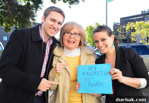 The authors posing with Aunt Liz and her friend Joan, holding a handmade sign.
