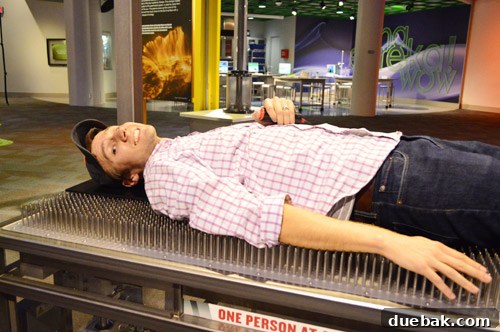 Swapping the Apple for the Peach 32 John lying on a bed of nails, appearing relaxed, at Discovery Place