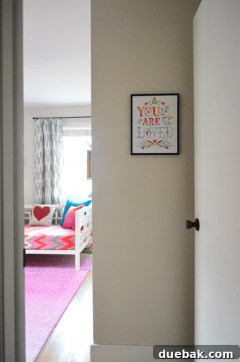A framed print by Katie Daisy, featuring colorful text and illustrations, hanging on a wall.